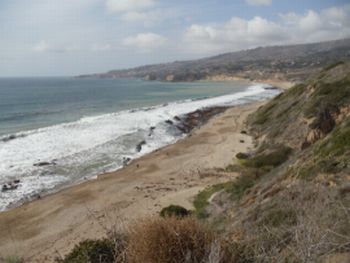 View from hill of waves rolling onto sandy beach